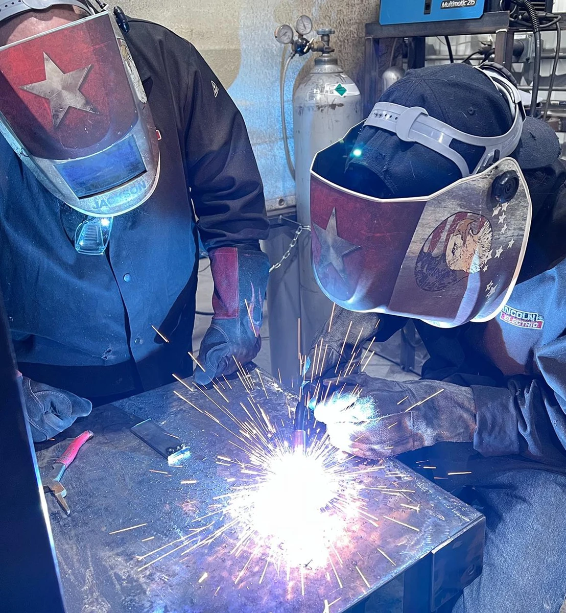 Two welders working together at a welding table